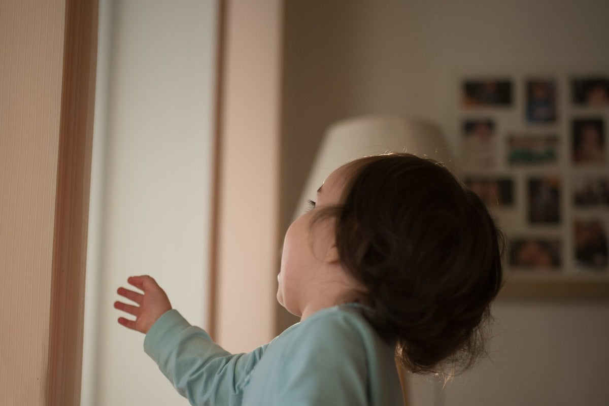 Child looking out a sunny window in a living room