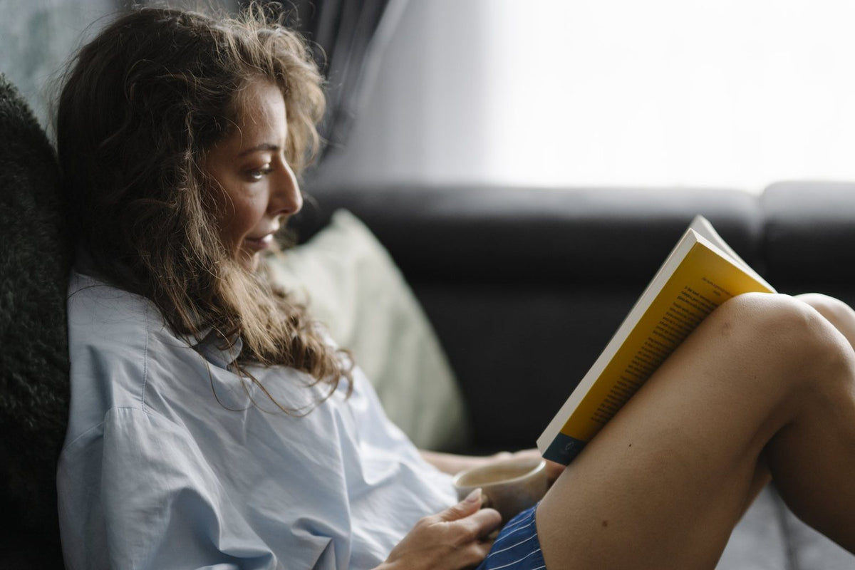 Woman reading on a couch by a sunny window