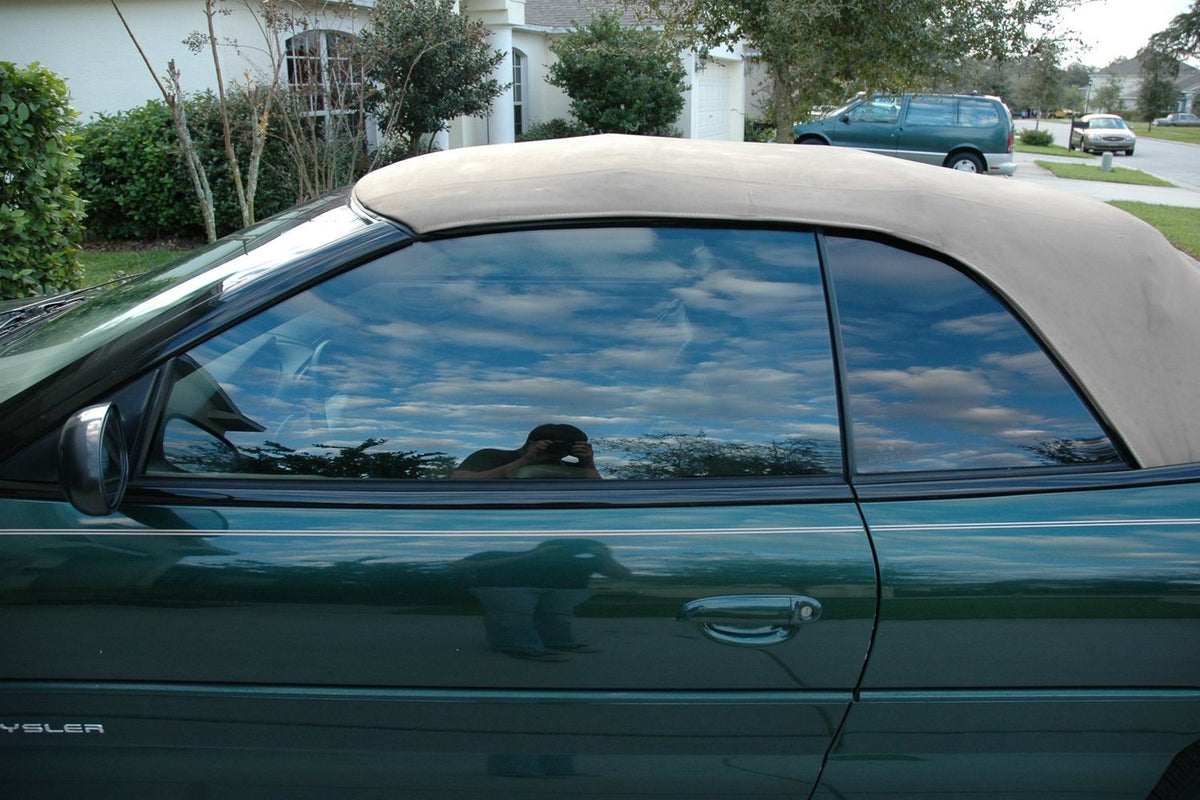 Side window of a car with tinted glass reflecting the sky